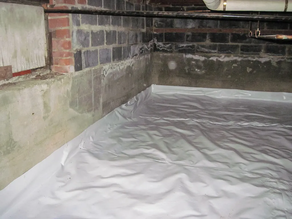 A white liner sealed over a crawl space floor and up its block walls