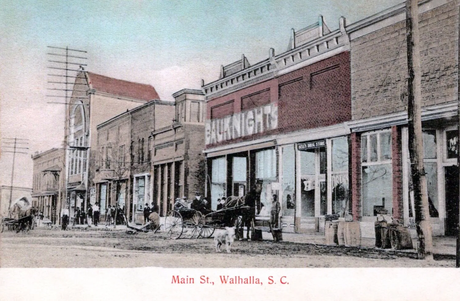 Main Street, Walhalla, on a 1908 postcard, with brick storefronts, a horse and buggy, and people along the sidewalk